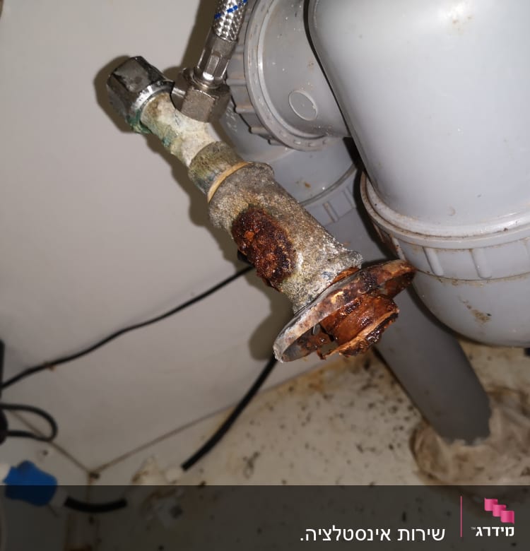 צינור חלוד עם חיבורי אינסטלציה מתחת לכיור